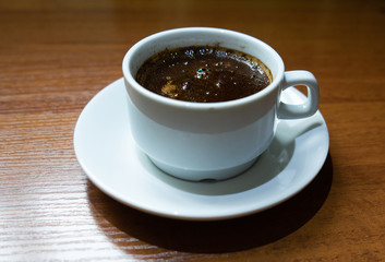 White Cup with black coffee on a wooden table