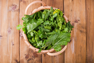 Raw Organic Turnip Greens Ready to Eat on a brown wooden background . basket with fresh green vegetables . Italian food. Above