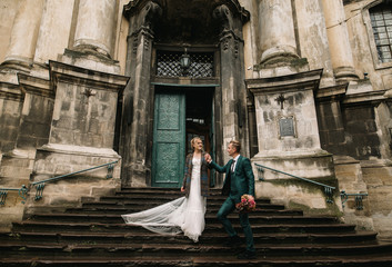 the groom helps the bride to go down the steps of the old temple