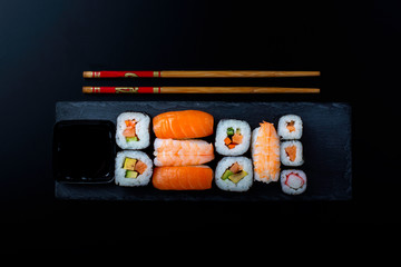 sushi on a black stone accompanied by two chopsticks