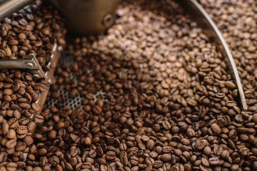 Freshly light roasted arabica coffee beans cooling in a roasters drum. Close up shot.
