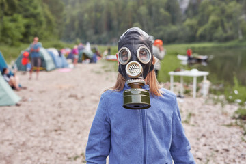 A girl of thirteen in a gas mask in the background of the tourist camp