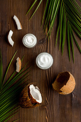 Fototapeta na wymiar Skin care cream with coconut oil on dark wooden background top-down
