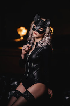 sexy woman in catwoman suit staying on stairs at backyard of building