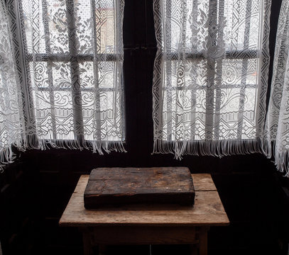 Ventana t&iacute;pica andaluza con visillos blancos y mesa de madera