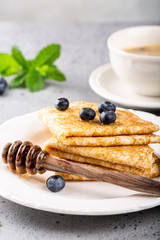 Delicious Tasty Homemade crepes or pancakes with blueberries, honey and mint on white plate. Healthy breakfast concept, gluten free.