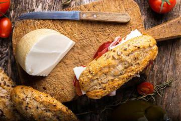 jamón ibérico y pan con pepitas sobre una mesa rústica acompañado de ingredientes