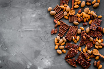 Sweets frame. Broken chocolate slices and nuts on grey stone background top-down copy space