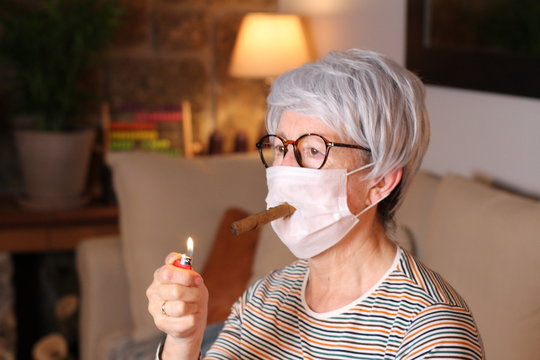 Senior woman smoking a cigar during viral outbreak