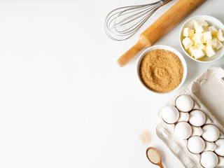 Various baking ingredients - eggs, sugar, butter, dry yeast and kitchen utensils on white...