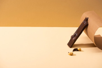 delicious dark chocolate with nuts piece and paper on beige background