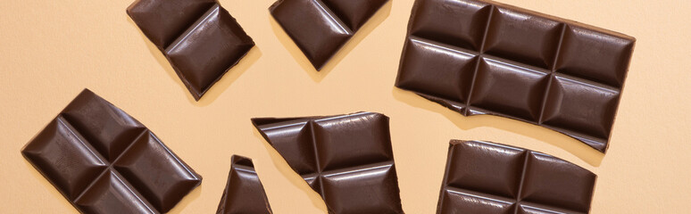 top view of delicious dark chocolate pieces on beige background, panoramic shot