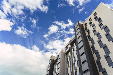 Fototapeta premium Block of tall residential buildings with clouds in the background at sunset sun.