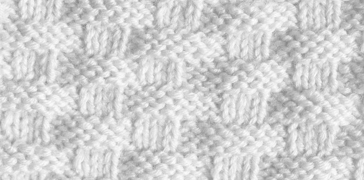 Texture pattern knitting with acrylic thread. Manual work with knitting needles, white background of wool.