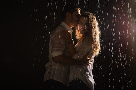 Young couple of lovers sharing romantic moments under the rain. Kissing and have fun under the rain