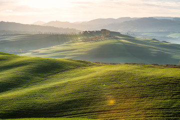 Amazing spring landscape with green rolling hills and farm houses in the heart of Tuscany in morning haze - obrazy, fototapety, plakaty