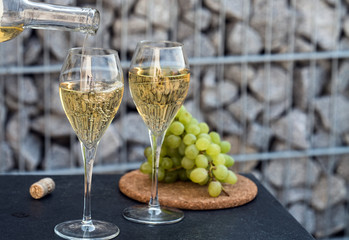 Waiter pouring white wine on outdoor cafe terrace in sunny summer day