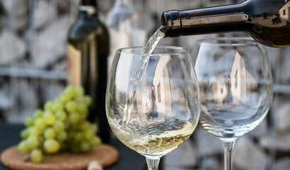 Waiter pouring white wine on outdoor cafe terrace in sunny summer day