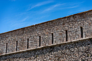 Fototapeta na wymiar Castello del Buonconsiglio or Castelvecchio Medieval castle in Trento city. Closeup of the fortified wall with the arrow slits or loopholes. Trentino Alto Adige, Italy, Europe