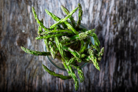 vista cenital de un contenedor de cristal con esparragos trigeros sobre un fondo r&uacute;stico.