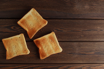 Several slices of toasted bread toasts on a wooden dark background.