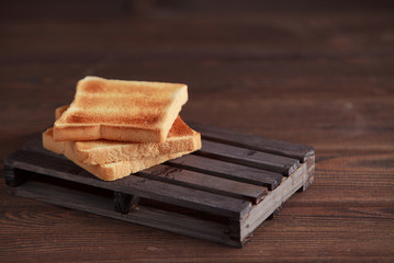 Several slices of toasted bread toasts on a wooden dark background.