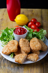 chicken nuggets with ketchup on a plate on a rustic table