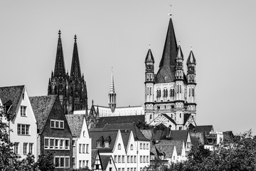 Fototapeta na wymiar Black and white skyline of the old town with houses rooftops, the tower of the Cologne gothic cathedral and the tower of Gtreat St. Martin church in Cologne, North Rhine Westphalia, Germany