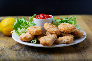 chicken nuggets with ketchup on a plate on a rustic table