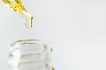 Close-up oil face moisturizer drop in glass bottle on white background with copy space. Skincare...