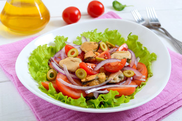 Salad of marinated mussels, fresh tomatoes, red onions, olives in a bowl on a white wooden background