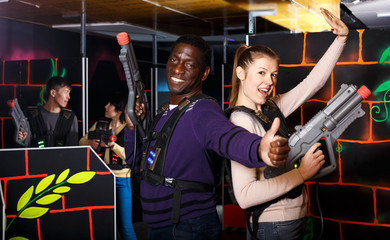 couple standing back to back holding laser guns during lasertag game
