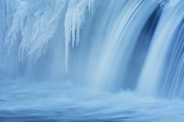 Fototapeta na wymiar Winter, Portage Creek Cascade captured with motion blur and framed by ice, Milham Park, Kalamazoo, Michigan, USA 