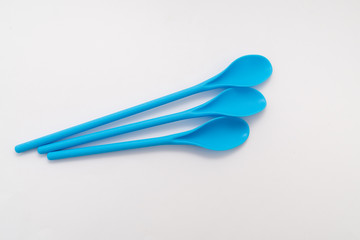 three blue kitchen plastic spoons on white background
