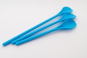 three blue kitchen plastic spoons on white background