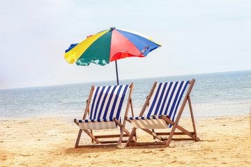Beach chairs with umbrella at beach with sand and sea