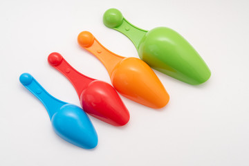 four multi-colored plastic kitchen spoons on white background