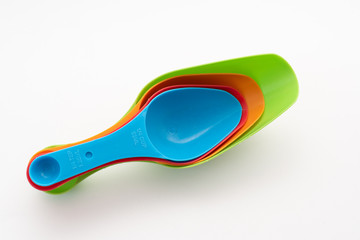 four multi-colored plastic kitchen spoons on white background
