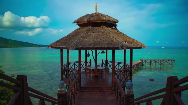 Beautiful 4K Cinemagraph / seamless video loop of a luxury tropical seaside vacation resort with a dining pavilion by the blue / turquoise seaside water and a coral reef on an island paradise in Asia.