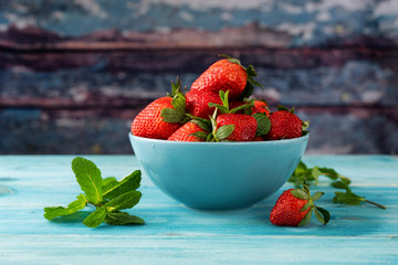 Juicy strawberry in a blue bowl against rustic background