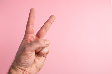 A male hand is displaying the v for victory sign