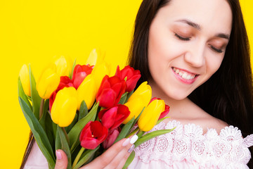 Birthday. Birthday girl with a bouquet of tulips. Woman portrait on a yellow background with tulips.
