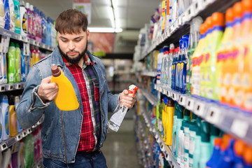 Stylish bearded guy buying household chemicals in supermarket