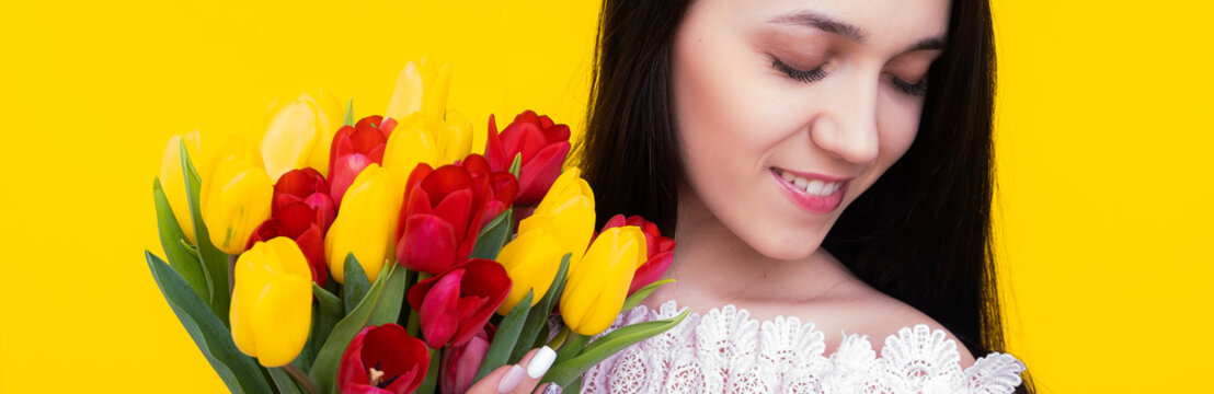 Portrait of a young brunette woman with a bouquet of tulips on a yellow banner background. Banner. Birthday. Women's Day. Mothers Day. Teacher's Day. - Powered by Adobe