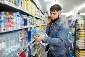 man buying still water in grocery section