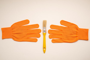 Obraz premium Orange work gloves and brush on white background