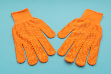 Orange work gloves isolated on blue background