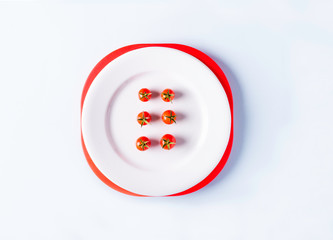 plato con tomates cherry ordenados sobre un fondo blanco
