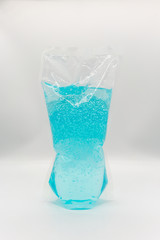 Coronavirus hand sanitizer gel to wash hands for flu virus prevention. Blue gel in clear plastic bag on white