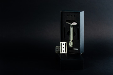 metallic safety razor with blades and soft shaving brush on dark background 